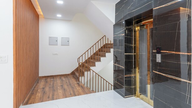 A modern interior with a wooden staircase, a marble floor, and a black-tiled wall. - Park Pacific By Saavi Hotel (Gurugram)