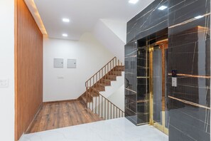 Ein modernes Interieur mit einer Holztreppe, einem Marmorboden und einer Wand mit schwarzen Fliesen.