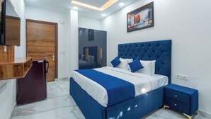 A bedroom with a large bed, a wooden wardrobe, a desk, and a ceiling fan. - Park Pacific By Saavi Hotel (Gurugram)