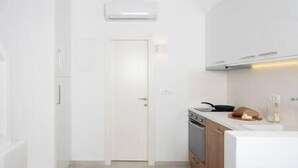 A modern kitchen with white cabinetry, a built-in oven, and a stainless steel range hood.