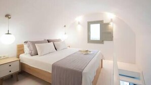 A bedroom with a bed, bedside table, and a wall-mounted light fixture.