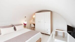 A bedroom with a bed, a wardrobe, a desk, and a chair. - White Orchid Suites | 2 | Heated Shared Mini Pool (Vothonas)