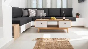 Ein modernes Wohnzimmer mit einem dunkelgrauen Sofa, zwei Beistelltischen und einem Holztisch.