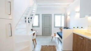 Un espace de vie moderne et compact comprenant un escalier, un coin repas et une cuisine.
