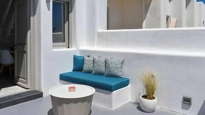Un espace extérieur moderne, aménagé avec un canapé bleu, une table ronde et une plante en pot.