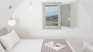 Une chambre à coucher comprenant un lit, une table de chevet, une fenêtre donnant sur un paysage et un luminaire fixé au mur.