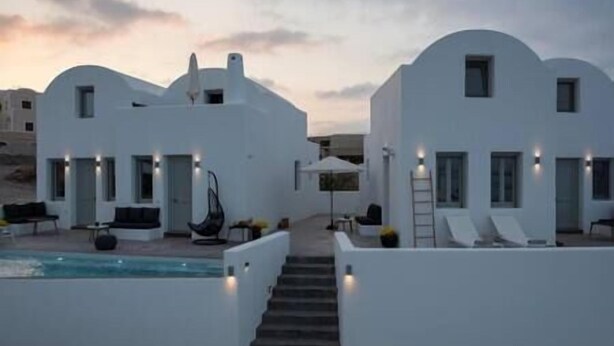 Una villa moderna y blanca con piscina, mobiliario exterior y una escalera que lleva a la entrada.