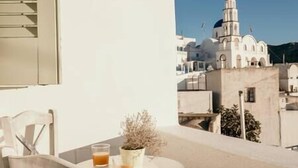 A balcony with a table, a chair, a glass of orange juice, and a potted plant.