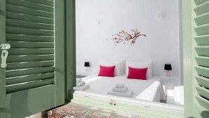 A bedroom with a bed, two bedside tables, a wall-mounted lamp, and a decorative wall piece.