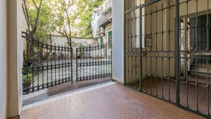 Un patio amurallado con suelo de baldosas, una reja metálica y una escalera que sube a un nivel superior.