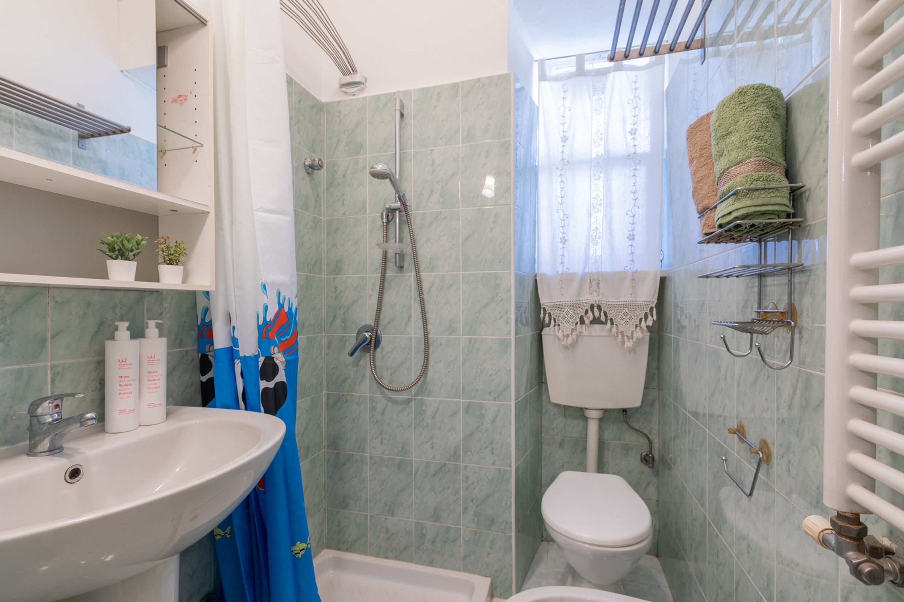 A bathroom with a sink, toilet, shower, and towel rack.
