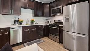 Una cocina moderna con gabinetes de madera oscura, electrodomésticos de acero inoxidable y un horno empotrado.