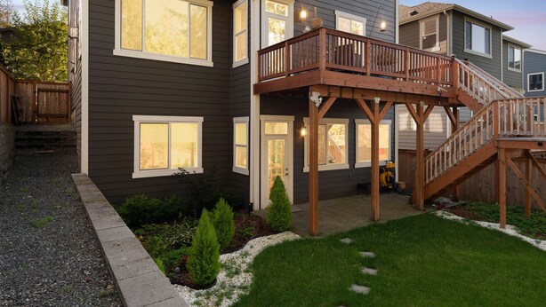 Una casa de varios pisos con un balcón de madera y una escalera que sube al nivel superior.