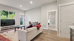 Una sala de estar moderna con sofá, televisor y comedor.