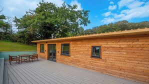 Een houten hut met een terras, een tafel en stoelen.