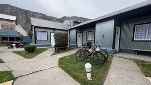 A courtyard with a bicycle, a bench, and a small garden area. - Complejo Don Joel (El Chalten)