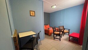 A room with a bed, a desk, two chairs, and a red chair. - Complejo Don Joel (El Chalten)