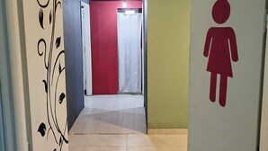 A hallway leading to a bathroom with a red door and a sign indicating the bathroom. - Complejo Don Joel (El Chalten)