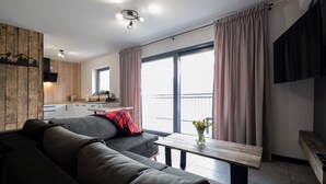 A modern living room with a sofa, a small table, and a kitchen area in the background.