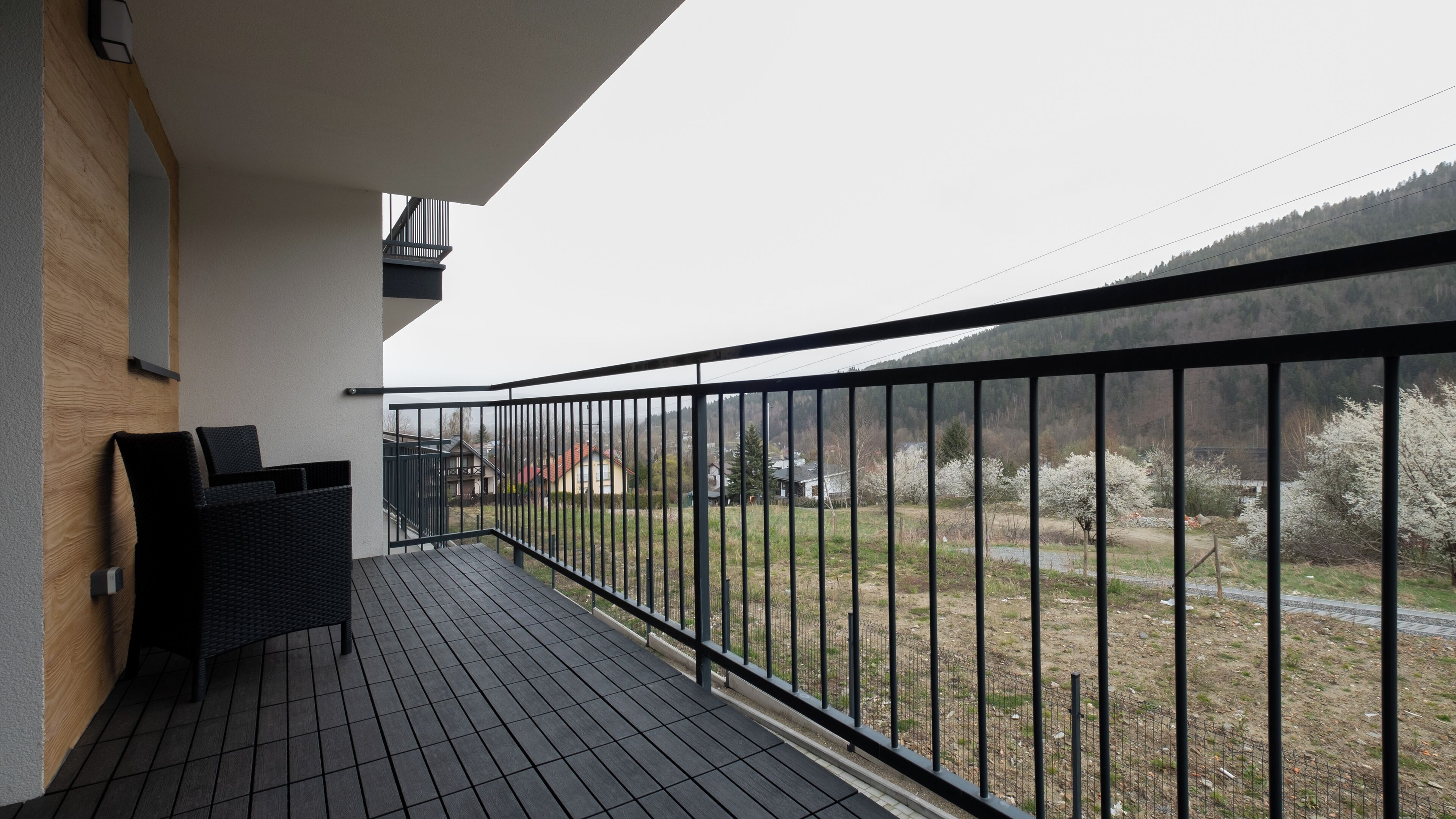 Un balcon avec une balustrade noire, une petite table et deux chaises.