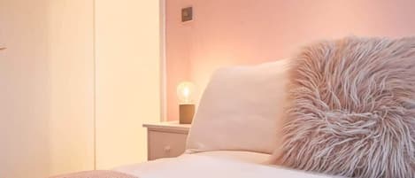 A bedroom with a bed, a nightstand, and a lamp.