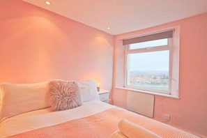 Une chambre à coucher avec un lit, une table de chevet, une fenêtre et une vue sur l’extérieur.