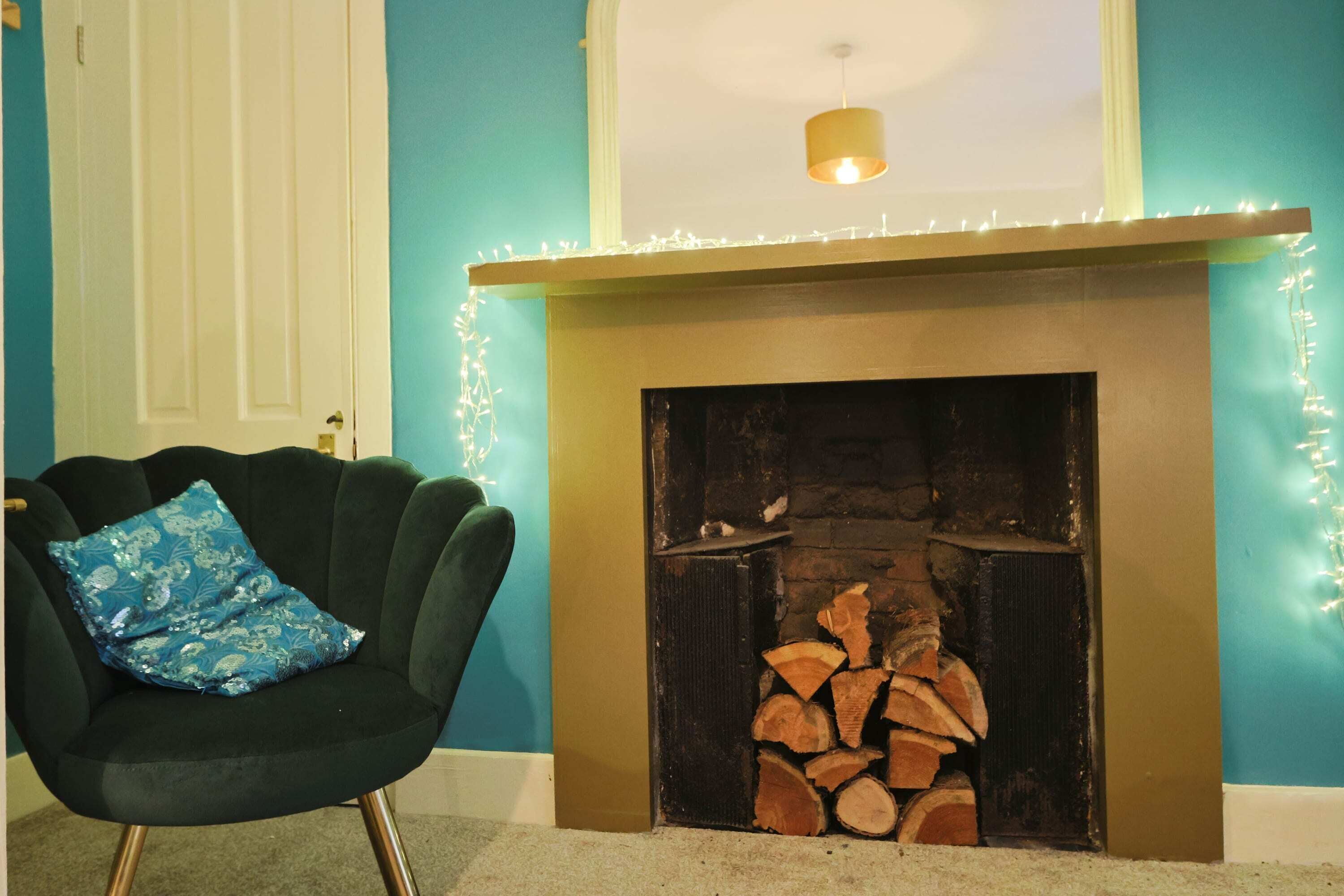 Une pièce avec une cheminée, un fauteuil doté d’un coussin à motifs et une porte.