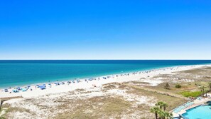 Uma praia com piscina, guarda-sóis e um céu azul límpido.