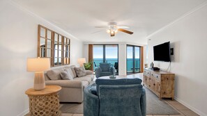 A living room with a sofa, armchairs, a TV, and a balcony with a view.