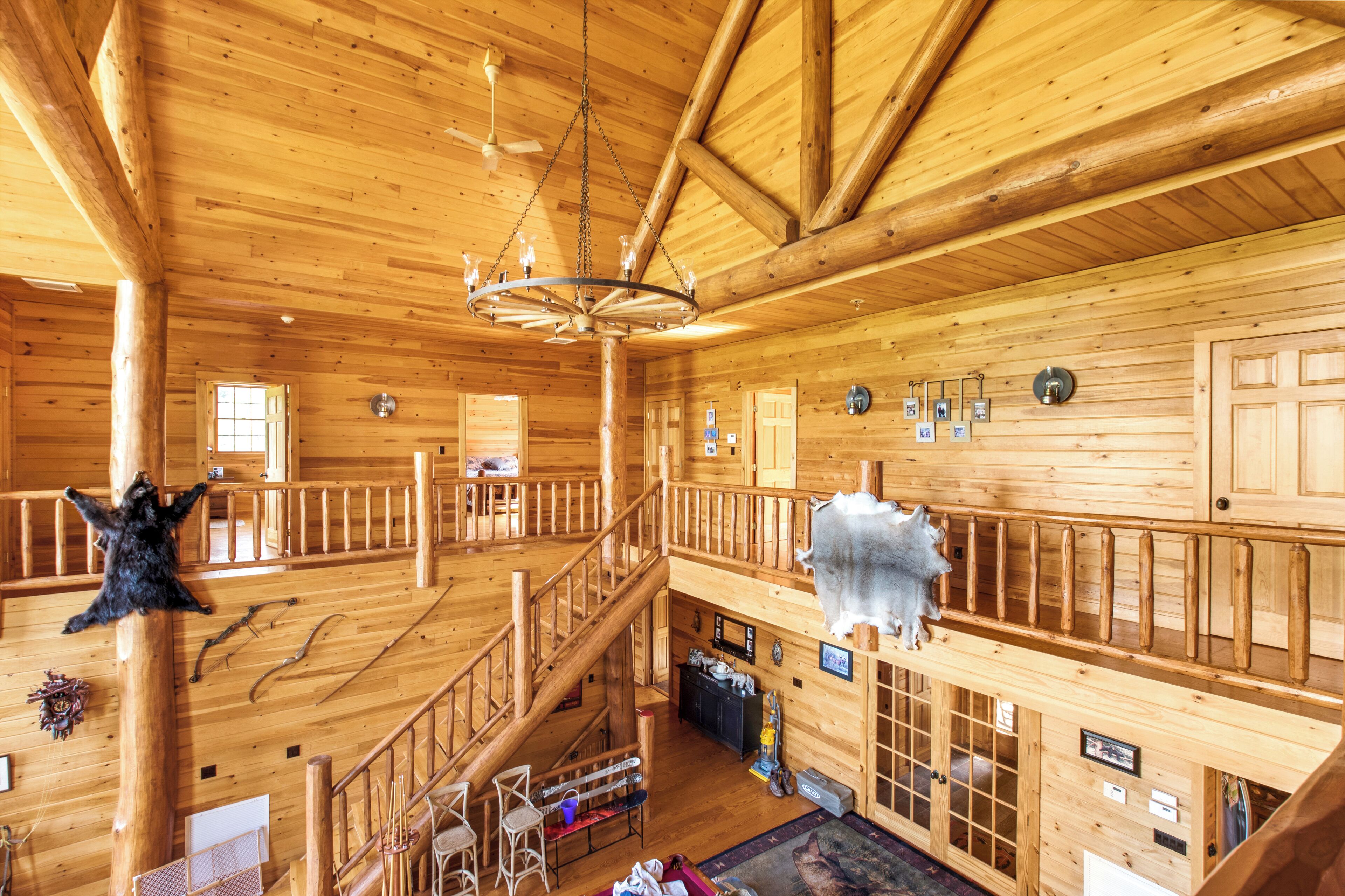 A spacious wooden cabin with a high ceiling, a central staircase, and a chandelier.