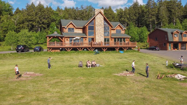 A lodge with a large deck, multiple windows, and a stone chimney.