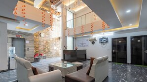 Una hall moderna con pavimento in marmo, divani in pelle, un tavolino da caffè in vetro e un camino.