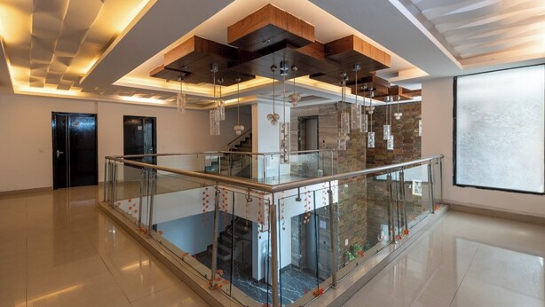 Un'ampia hall con balcone a parapetto in vetro, una scala e un moderno design del soffitto.