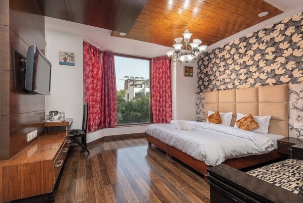 Un dormitorio con techo de madera, un ventanal con cortinas rojas, una cama con ropa blanca y una pared con diseño.