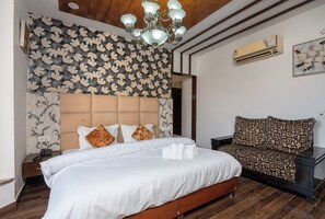 Un dormitorio con cama, sofá, candelabro y papel tapiz estampado.