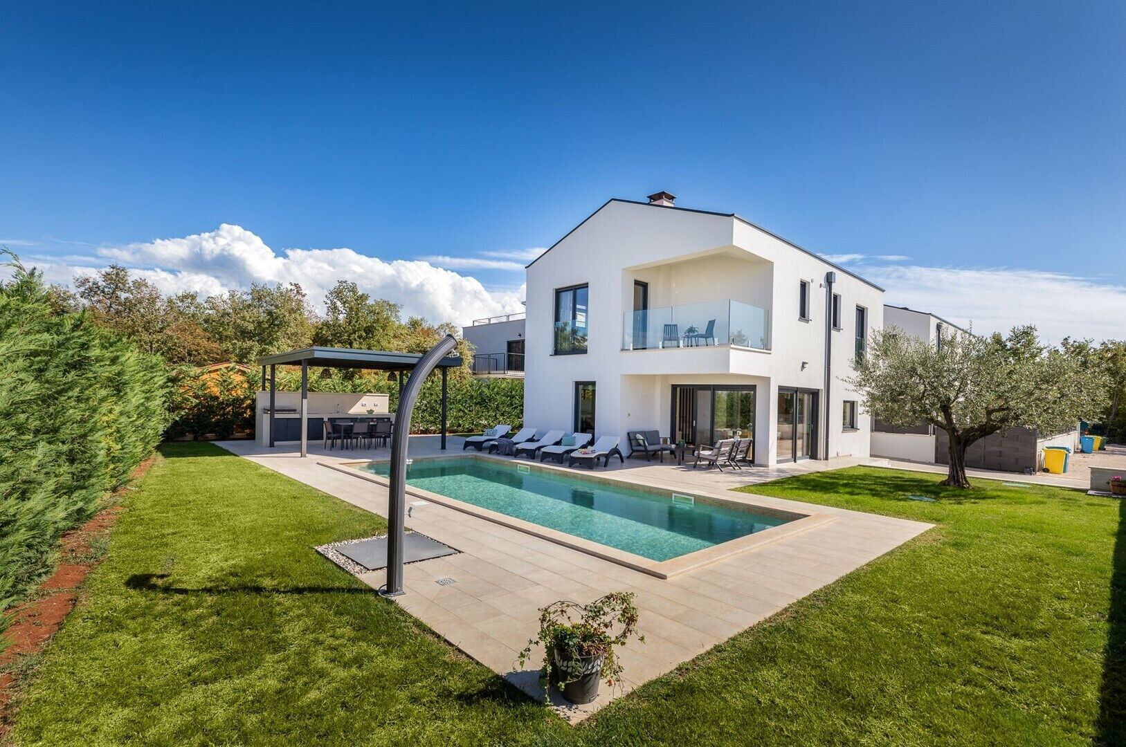A modern two-story house with a swimming pool, outdoor seating, and a covered patio.