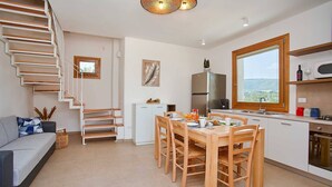 Eine moderne Küche mit Essbereich, einer Treppe und Blick ins Freie.
