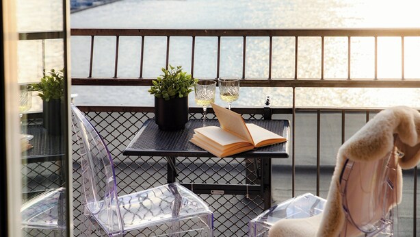 Ein Balkon mit Tisch, Stühlen, einer Topfpflanze und Blick auf einen Fluss.