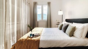 Ein Hotelzimmer mit Bett, Nachttisch mit Frühstücksutensilien, Fenster mit Vorhängen und einer Lampe.