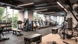 A gym with various exercise equipment, large windows, and a view of palm trees.