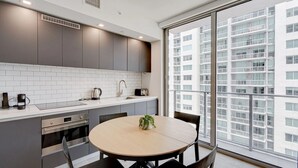 A modern kitchen with grey cabinets, a white countertop, and a round dining table with chairs.