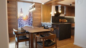 A modern kitchen with wooden cabinets, a marble countertop, and pendant lighting.