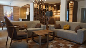 A modern living room with a sofa, armchairs, a coffee table, and a wine rack.