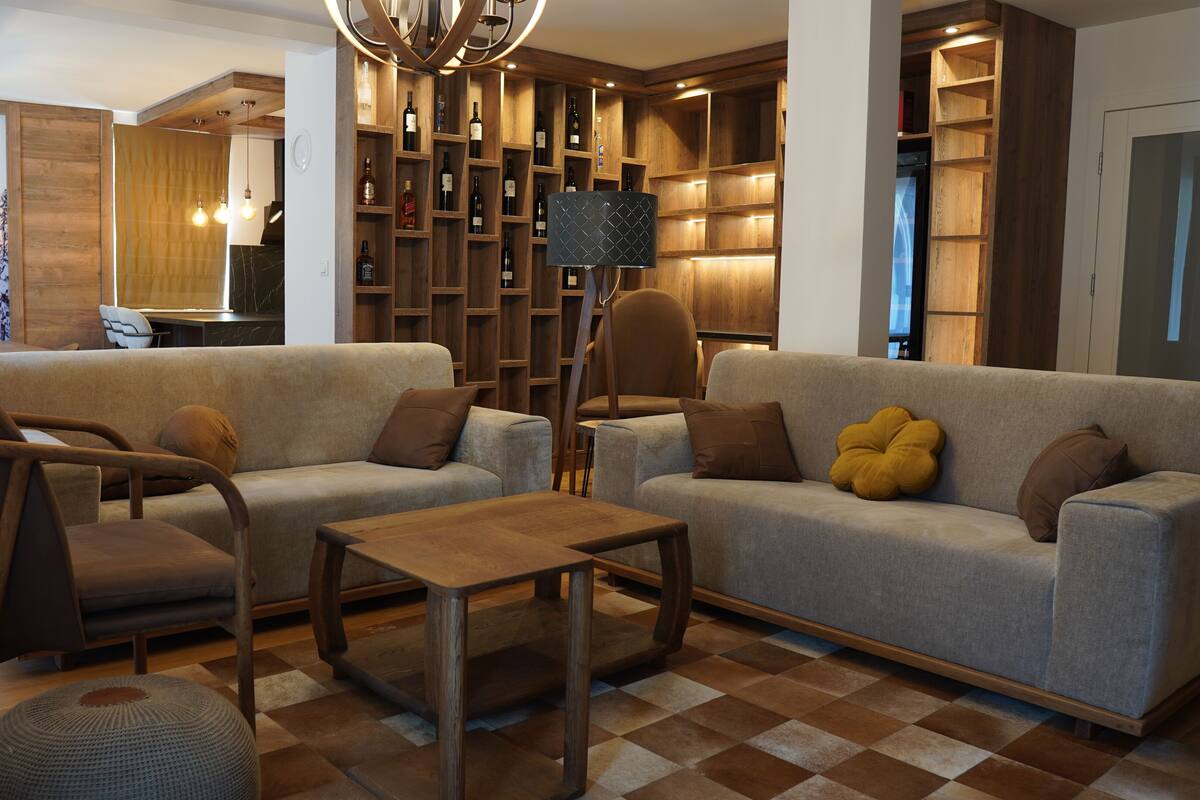 Una sala de estar moderna con un sofá, sillones, una mesa de centro y un botellero.