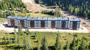 A multi-story hotel with a modern design, located in a mountainous area with a ski lift in the background.