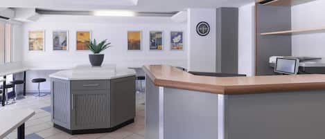 A modern kitchen with a central island, bar stools, and a potted plant.