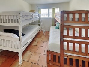 Un dormitorio con dos literas, una ventana con cortinas y un radiador.