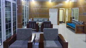 A spacious living area with a sofa set, a coffee table, and a TV. - Secret Paradise Sylhet (Sylhet)