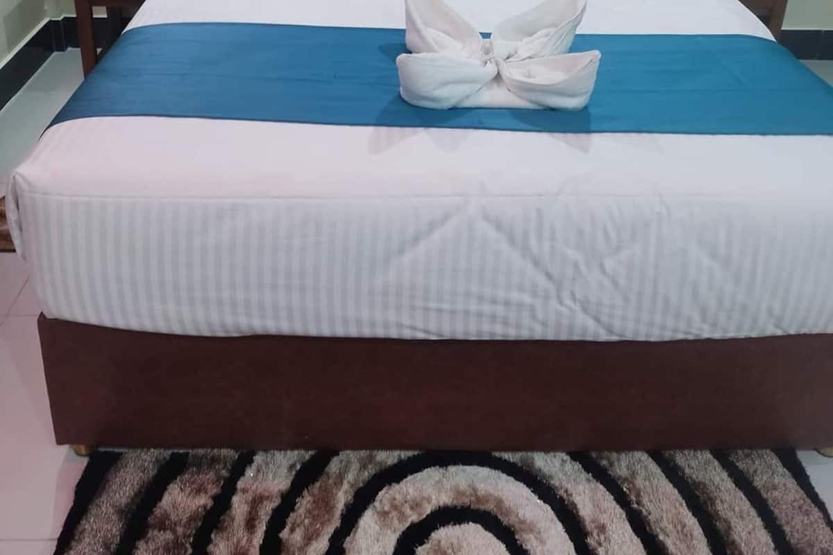 A neatly made bed with a blue and white bedspread, a wooden headboard, and a decorative towel on the bed.