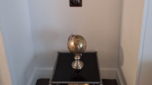 A corner with a black square table holding a globe, two framed artworks on the wall, and a dark wooden floor. - DOWNTOWN AT CUTE AND COZY  (Atlanta)